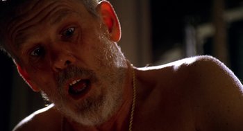 Movie still from “U Turn” (1997), directed by Oliver Stone – An old man with a beard and a necklace; Close Up shot, Low angle
