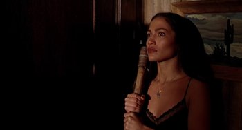 Movie still from “U Turn” (1997), directed by Oliver Stone – A woman in a black top holding a wooden stick; Close Up shot, High angle