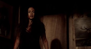 Movie still from “U Turn” (1997), directed by Oliver Stone – A woman in a black shirt is standing in the dark; Medium shot, Low angle