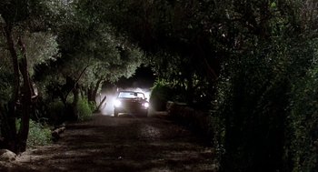 Movie still from “U Turn” (1997), directed by Oliver Stone – A car driving down a dirt road at night; Extreme Wide shot, Low angle