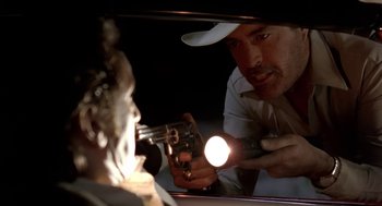 Movie still from “U Turn” (1997), directed by Oliver Stone – A man holding a gun in front of a man with a flashlight; Close Up shot, Over the shoulder angle
