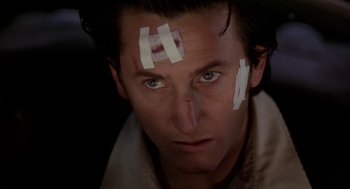 Movie still from “U Turn” (1997), directed by Oliver Stone – A person with bandaids on their face; Close Up shot, Low angle