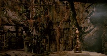 Movie still from “UHF” (1989), directed by Jay Levey – A statue of an oscar in front of a stone wall; Extreme Wide shot, High angle