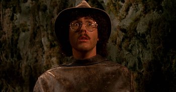 Movie still from “UHF” (1989), directed by Jay Levey – A man in a hat and glasses is standing in front of a wall; Close Up shot, Low angle