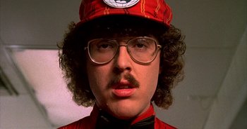 Movie still from “UHF” (1989), directed by Jay Levey – A man in a red hat and glasses; Close Up shot, Low angle