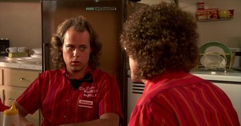 Movie still from “UHF” (1989), directed by Jay Levey – A man in red shirt looking in the mirror; Close Up shot, Over the shoulder angle