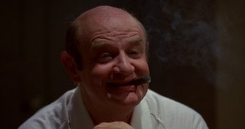 Movie still from “UHF” (1989), directed by Jay Levey – An older man smoking a cigarette while wearing a white shirt; Close Up shot, Low angle