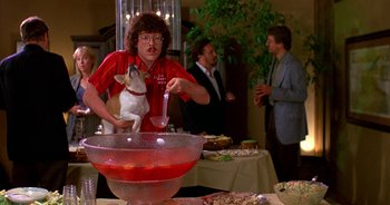 Movie still from “UHF” (1989), directed by Jay Levey – A man holding a dog in front of a bowl of food; Medium shot, Over the shoulder angle