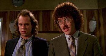 Movie still from “UHF” (1989), directed by Jay Levey – Two men in suits and ties standing next to each other in a room; Close Up shot, Low angle