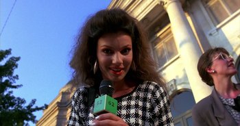 Movie still from “UHF” (1989), directed by Jay Levey – A woman is holding a microphone in her hand; Close Up shot, Low angle