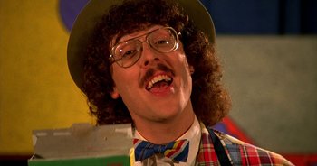 Movie still from “UHF” (1989), directed by Jay Levey – A man in a hat and a bow tie with curly hair; Close Up shot, Low angle