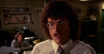Movie still from “UHF” (1989), directed by Jay Levey – A man in a tie and glasses with curly brown hair; Close Up shot, Low angle