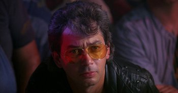 Movie still from “UHF” (1989), directed by Jay Levey – A man wearing a leather jacket and yellow glasses; Close Up shot, Low angle