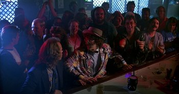 Movie still from “UHF” (1989), directed by Jay Levey – A group of people standing around a bar; Wide shot, Over the shoulder angle