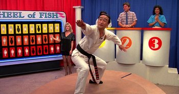 Movie still from “UHF” (1989), directed by Jay Levey – A man in a karate outfit is performing a move; Wide shot, Over the shoulder angle