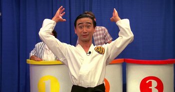 Movie still from “UHF” (1989), directed by Jay Levey – A man in a karate outfit with his hands raised; Medium shot, Low angle