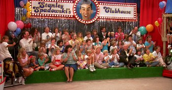 Movie still from “UHF” (1989), directed by Jay Levey – A group of people sitting on a stage; Wide shot, High angle