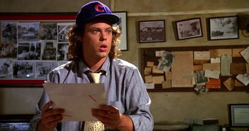 Movie still from “UHF” (1989), directed by Jay Levey – A man wearing a baseball cap holding a piece of paper; Close Up shot, Over the shoulder angle