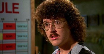 Movie still from “UHF” (1989), directed by Jay Levey – A man with curly brown hair and glasses; Close Up shot, Low angle