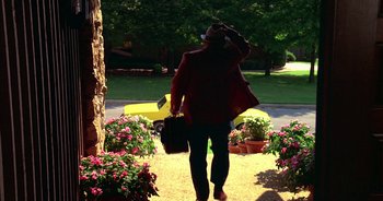 Movie still from “UHF” (1989), directed by Jay Levey – A woman in a red jacket holding a suitcase; Wide shot, Low angle