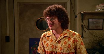 Movie still from “UHF” (1989), directed by Jay Levey – A man with a curly hair and glasses in a room; Close Up shot, High angle