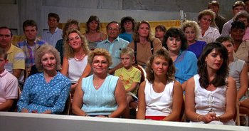 Movie still from “UHF” (1989), directed by Jay Levey – A large group of people sitting in a room together; Wide shot, High angle