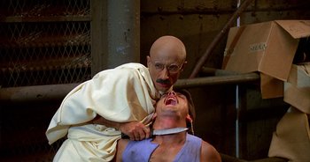 Movie still from “UHF” (1989), directed by Jay Levey – A man is being held down by a bald man; Close Up shot, High angle