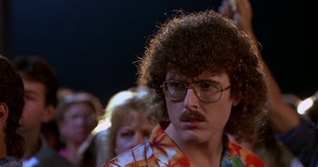 Movie still from “UHF” (1989), directed by Jay Levey – A man with curly brown hair wearing glasses and a hawaiian shirt; Close Up shot, Low angle