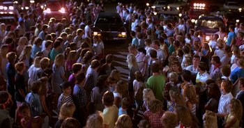 Movie still from “UHF” (1989), directed by Jay Levey – A crowd of people standing on the side of a road; Wide shot, High angle