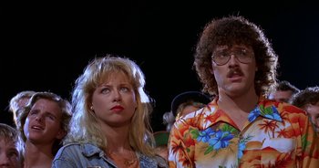 Movie still from “UHF” (1989), directed by Jay Levey – A man and a woman standing next to each other; Close Up shot, Low angle
