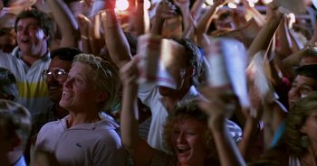 Movie still from “UHF” (1989), directed by Jay Levey – A group of people holding up cans at a concert; Medium shot, High angle