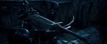 Movie still from “Underworld: Rise of the Lycans” (2009), directed by Patrick Tatopoulos – A man holding a bow and arrow in a dark room; Medium shot, Over the shoulder angle