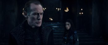 Movie still from “Underworld: Rise of the Lycans” (2009), directed by Patrick Tatopoulos – A man and a woman standing next to each other in front of stairs; Medium shot, Over the shoulder angle