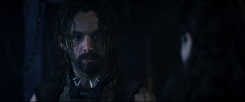 Movie still from “Underworld: Rise of the Lycans” (2009), directed by Patrick Tatopoulos – A man with long hair and a beard wearing a spiked collar; Close Up shot, Over the shoulder angle