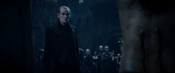Movie still from “Underworld: Rise of the Lycans” (2009), directed by Patrick Tatopoulos – A group of people standing in front of a building; Medium shot, Over the shoulder angle