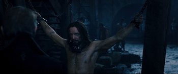 Movie still from “Underworld: Rise of the Lycans” (2009), directed by Patrick Tatopoulos – A man with long hair is standing in the dark; Medium shot, High angle