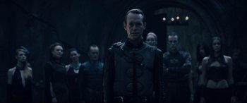Movie still from “Underworld: Rise of the Lycans” (2009), directed by Patrick Tatopoulos – A group of men standing next to each other in a dark room; Medium shot, Over the shoulder angle