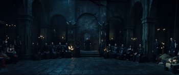 Movie still from “Underworld: Rise of the Lycans” (2009), directed by Patrick Tatopoulos – A group of people sitting on steps in front of a stone wall; Wide shot, High angle