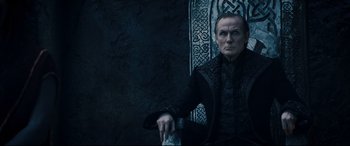 Movie still from “Underworld: Rise of the Lycans” (2009), directed by Patrick Tatopoulos – A man sitting on a chair in front of a wall; Medium shot, High angle