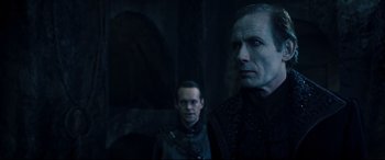 Movie still from “Underworld: Rise of the Lycans” (2009), directed by Patrick Tatopoulos – Two men are standing next to each other in a dark room; Medium shot, Over the shoulder angle