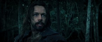Movie still from “Underworld: Rise of the Lycans” (2009), directed by Patrick Tatopoulos – A person with a beard in the woods; Close Up shot, Over the shoulder angle