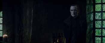 Movie still from “Underworld: Rise of the Lycans” (2009), directed by Patrick Tatopoulos – A man standing in the dark with a dark background behind him; Medium shot, Over the shoulder angle
