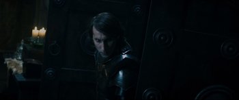Movie still from “Underworld: Rise of the Lycans” (2009), directed by Patrick Tatopoulos – A man in a dark room wearing a metal armor; Close Up shot, Over the shoulder angle