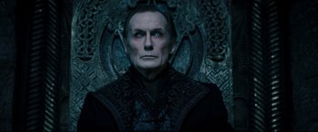 Movie still from “Underworld: Rise of the Lycans” (2009), directed by Patrick Tatopoulos – An old man with blue eyes is standing in front of an ornate wall; Close Up shot, Low angle