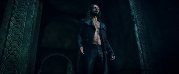 Movie still from “Underworld: Rise of the Lycans” (2009), directed by Patrick Tatopoulos – A man with long hair is standing in a dark room; Medium shot, Low angle