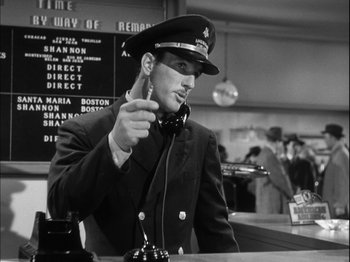 Movie still from “Unfaithfully Yours” (1948), directed by Preston Sturges – A man wearing a uniform and a hat is holding a microphone; Medium shot, Low angle