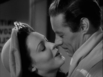 Movie still from “Unfaithfully Yours” (1948), directed by Preston Sturges – A man and a woman kissing each other in a black and white photo; Close Up shot, High angle