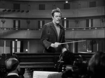 Movie still from “Unfaithfully Yours” (1948), directed by Preston Sturges – A man is playing a musical instrument in front of an audience; Medium shot, Low angle