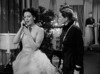 Movie still from “Unfaithfully Yours” (1948), directed by Preston Sturges – A woman in a white dress is singing into a microphone; Medium shot, Low angle