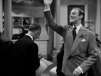 Movie still from “Unfaithfully Yours” (1948), directed by Preston Sturges – A black and white photo of a man in a suit waving; Medium shot, Over the shoulder angle